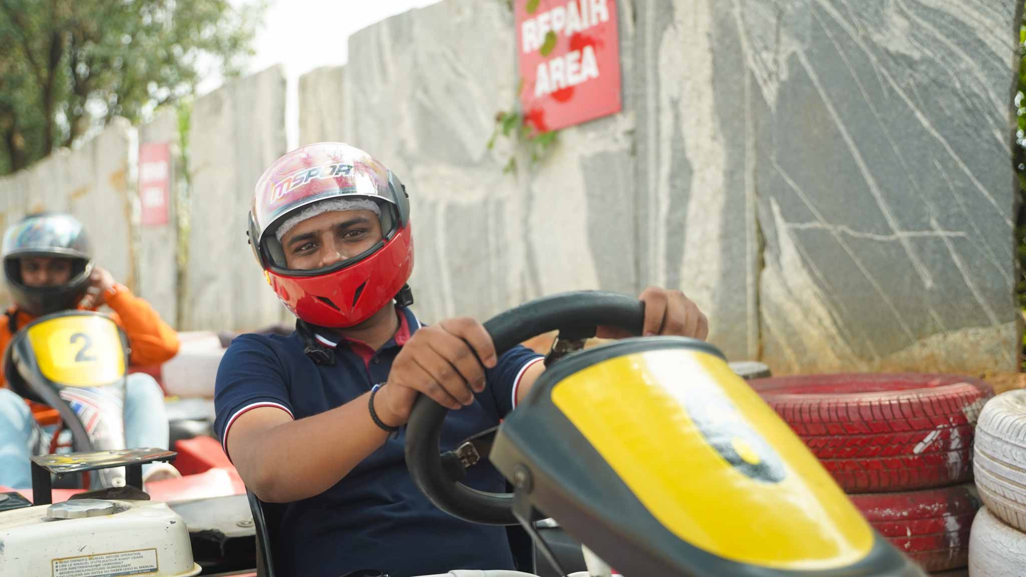 A driver with a red helmet focused on steering while in a go-kart.